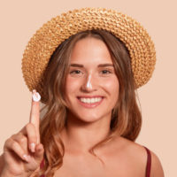 Young,Woman,Applaying,Sunblock,On,Her,Face,,And,Showinig,Her